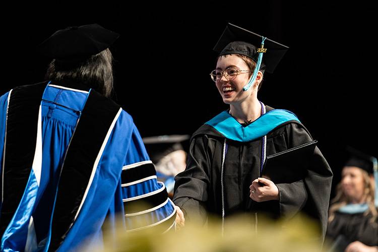 Person receiving a Master of Education diploma at GVSU commencement